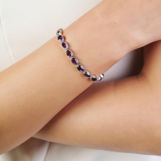 This elegant tennis bracelet is beautifully crafted in 925 sterling silver and set with 25 natural oval-cut amethysts,...