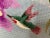 Hand made needlepoint featuring two hummingbirds in flight on a branch of irises. Background features three shades of...