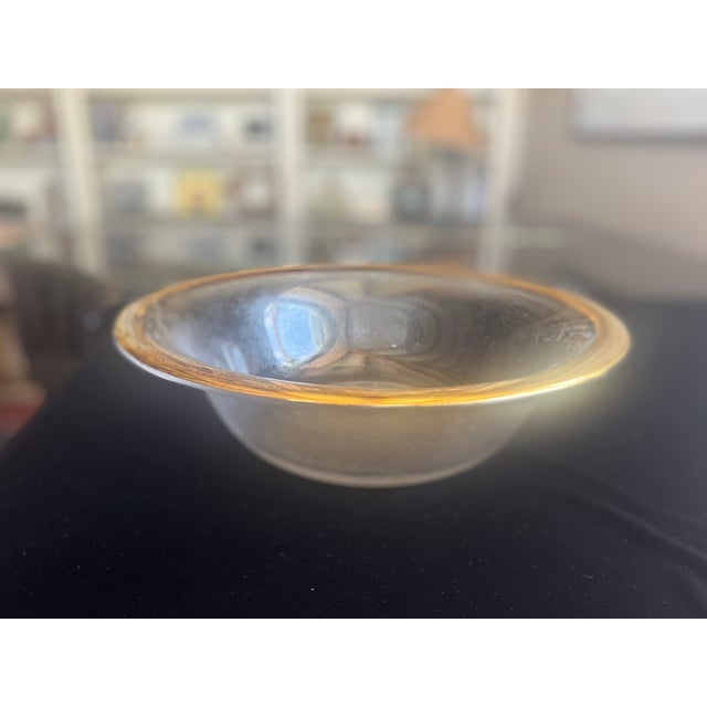 A large serving bowl in the Annieglass Roman Antique pattern, featuring clear hand-formed glass with a wide 24k gold rim....