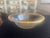 A large serving bowl in the Annieglass Roman Antique pattern, featuring clear hand-formed glass with a wide 24k gold rim....