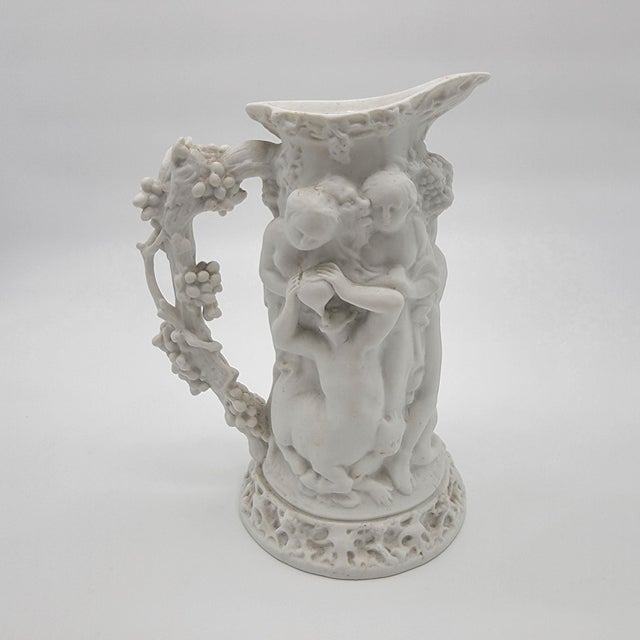 This antique Parian Ware pitcher showcases intricate figural scenes, including Triumph of Silenus and Bacchanalian Dance....