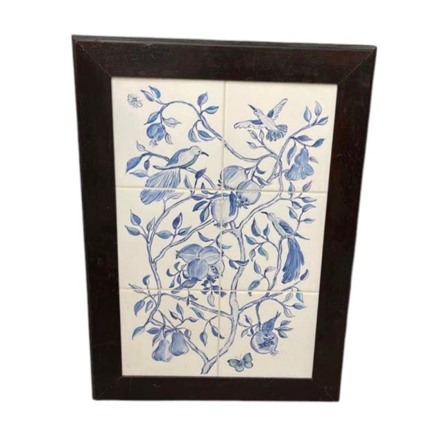 This framed ceramic tile wall art panel showcases a classic blue-and-white botanical scene inspired by traditional...
