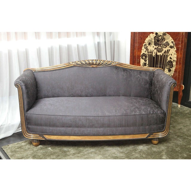 Smalll Art Deco sofa/loveseat with relief carving along the frame and ball feet in gold leaf. A stylized flower motif...
