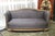 Smalll Art Deco sofa/loveseat with relief carving along the frame and ball feet in gold leaf. A stylized flower motif...