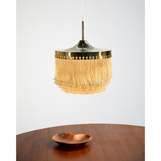 Brass pendant lamp with textile fringes, designed by Hans-Agne Jakobsson for Markaryd in the 1960s. Designed by Hans-Agne...