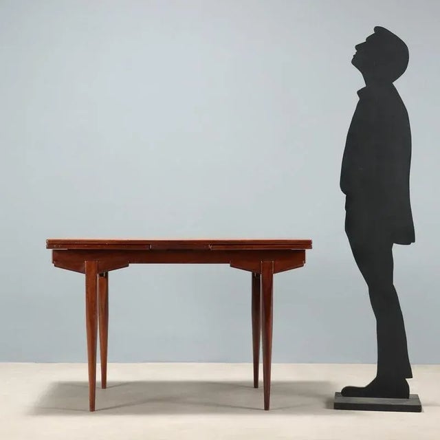 Vintage Italian-made dining table in teak veneer with a rectangular top that can be extended with extensions. This piece...