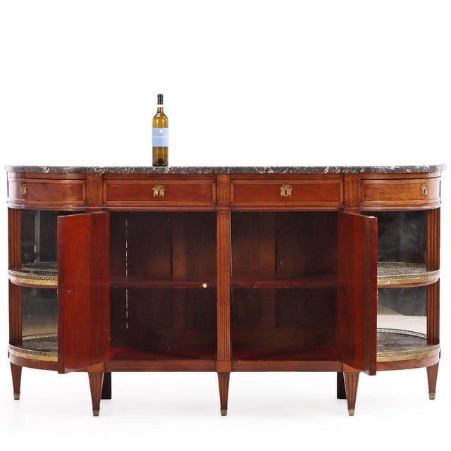 This elegant French Louis XVI-style demilune sideboard is beautifully crafted from mahogany and showcases a wonderfully...