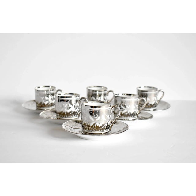 An antique set of 6 demitasse lusterware coffee cups and saucers (12 pieces total), in a delicate Lilies of the Valley...
