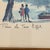 A charming mid-century Parisian scene depicting the Eiffel Tower from across the Seine, framed by leafy trees with a...