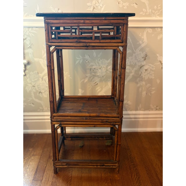 Chinese export side table in burnt tortoiseshell bamboo with black top. The apron features Chinese Chippendale fretwork...