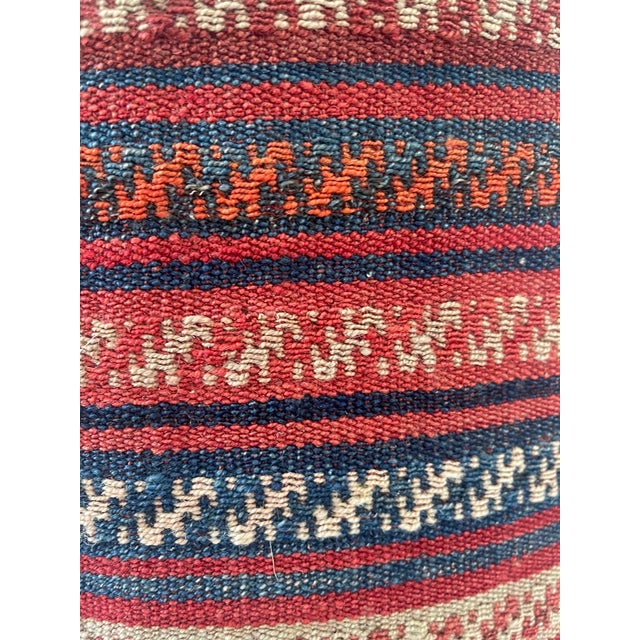 Vintage ottoman pouf upholstered with beautifully hand woven kilim rug, red, blue and cream stripes around base, and...