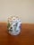 A petite porcelain jar featuring hand-painted floral motifs in soft pinks, greens, and delicate detailing. The domed lid...