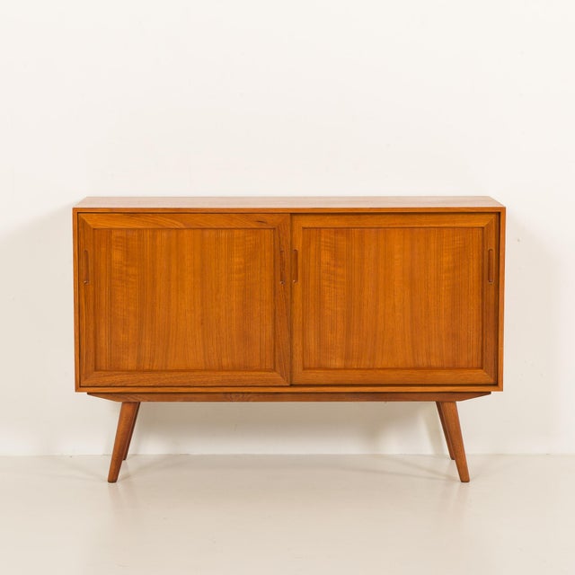 This vintage sideboard comes from the 1970s and shows the quality of mid-century Scandinavian carpentry with solid teak...