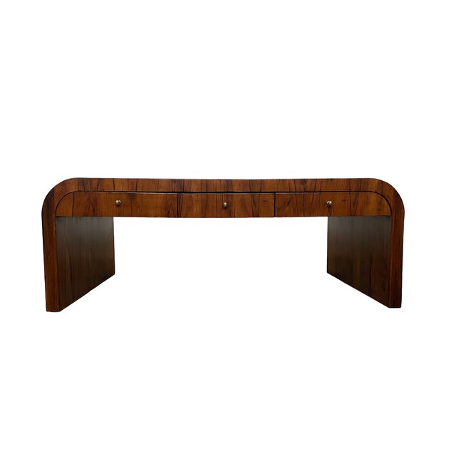 A sculptural early-20th-century Art Deco coffee table crafted in richly figured Brazilian rosewood veneer. Its rectangular...