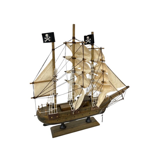 Wooden pirate ship model, featuring a detailed design with a natural wood hull and mast, fabric sails, classic pirate...