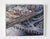 This mixed media piece on wood panel captures a dynamic urban landscape, showcasing an intricate network of highways and...
