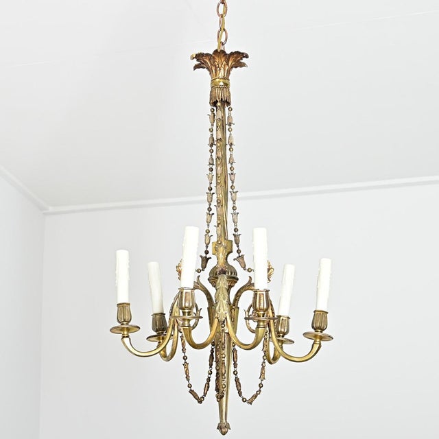 French, 19th century slender chandelier made of gilt bronze accented with dainty foliate and Neoclassical motifs in lieu...