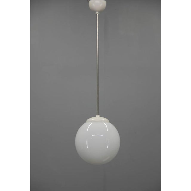 A timeless vintage pendant light from the 1940s, featuring a beautifully simple white opaline glass globe that embodies...