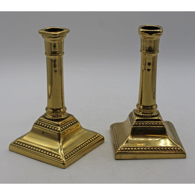 English Queen Anne, mid-18th century, pair of brass candlesticks. Square bases, ring turned shaft; shaped bases accented...