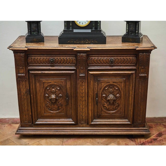 A representative piece of furniture made of solid walnut, decorated with rich hand carving. The front consists of a pair...