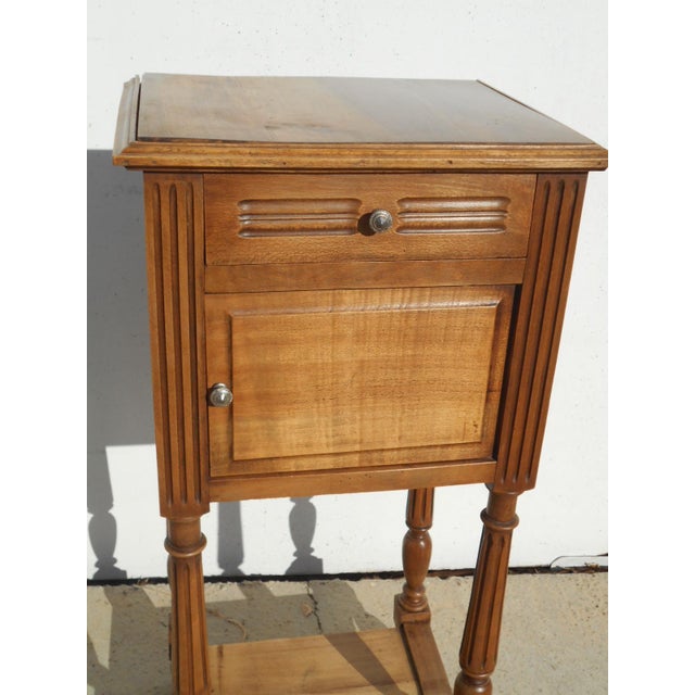A French-made bedside table, manufactured in Revel, mid-20th century, in the Louis XVI style, crafted from solid walnut....