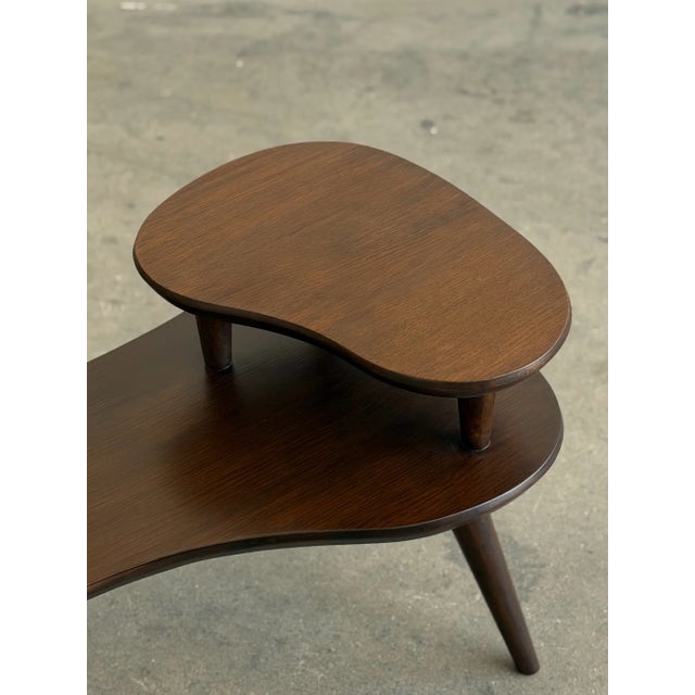 W29.5 D19 H21.5 Vintage oak two-tier side table featuring a sculptural Mid-Century Modern design. This unique piece has...