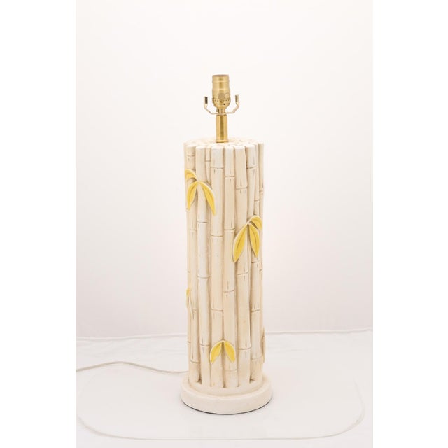 A whimsical pair of faux bamboo ceramic lamps accented with delicate yellow leaves and textured surfaces. Inspired by mid-...