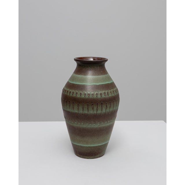 This 20th Century German ceramic vase features a refined blend of earthy tones and subtle geometric detailing,...