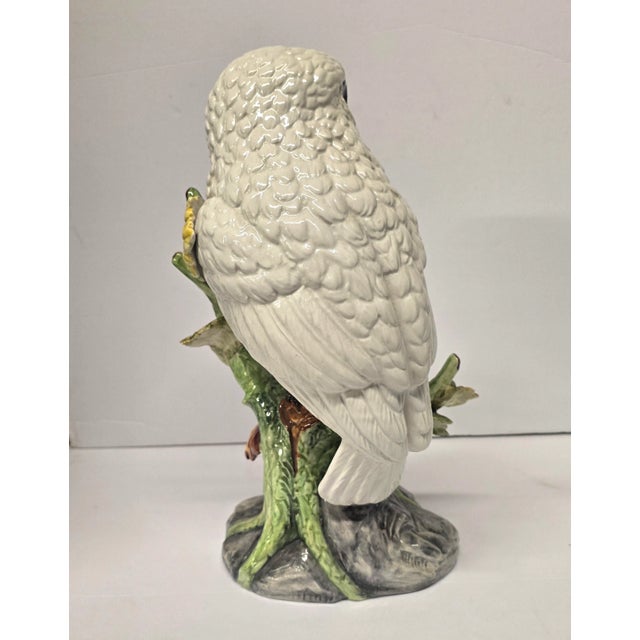 Beautiful white ceramic owl perched on a tree branch.The eyes are striking, so intense.The bird is looking around, almost...