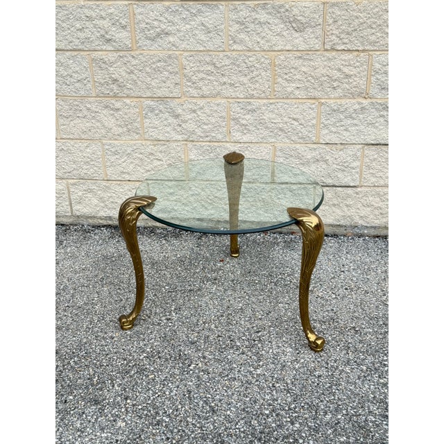 Rare vintage side table in the style of P.E. Guerin, featuring sculpted frond-style legs and a thick round glass top. The...