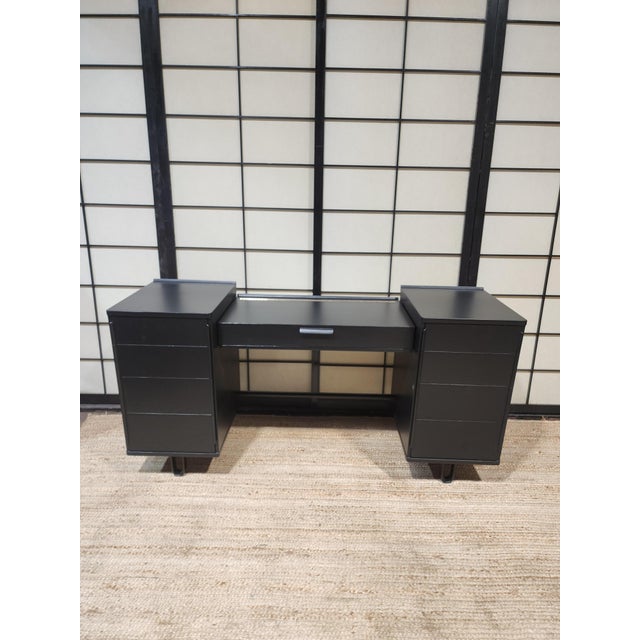 A striking mid-century modern modular vanity desk featuring a dramatic matte black ebonized finish. The architectural...