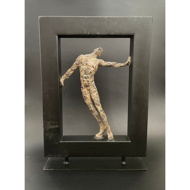 A Brutalist sculpture of a distressed nude figure nested in a display frame by Austin Productions. Estimated material:...