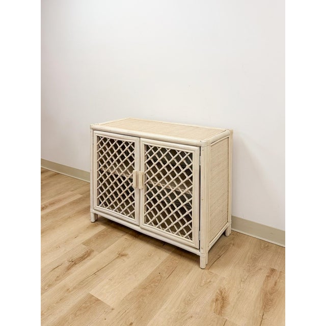 This lovely vintage cream rattan lattice cabinet is a warm and beautifully detailed coastal and Hollywood Regency...