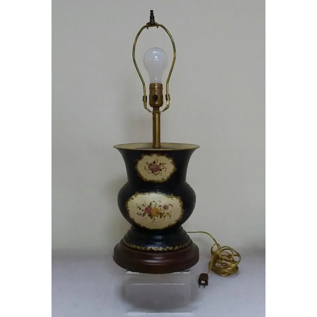 Pretty 20th C Painted tole lamp with dark blue background and floral painted sections on the front and back.