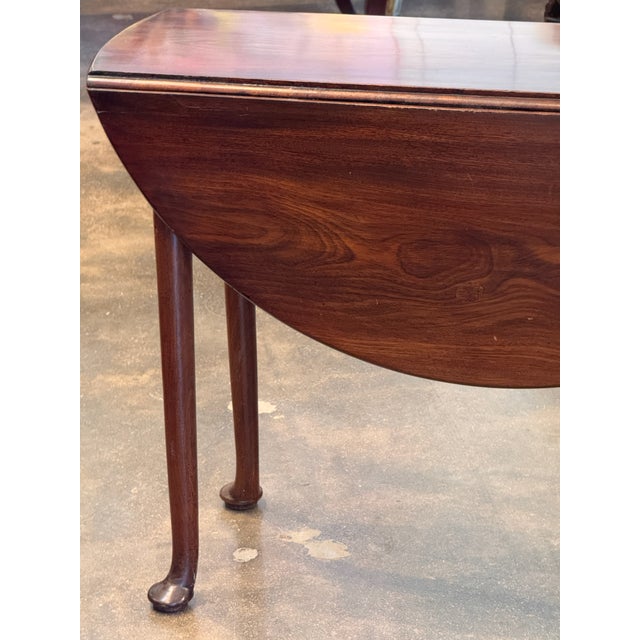 A George III mahogany drop-leaf table with a shaped apron and slender turned legs. The top retains its original drop...