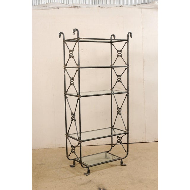 A French Giacometti inspired open display metal étagère with glass shelves. This vintage open case shelving from France...