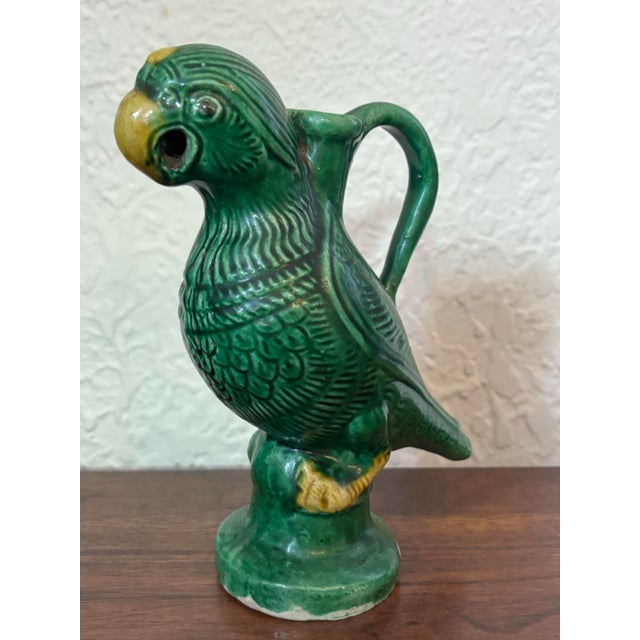 A late-19th or early-20th century porcelain parrot ewer finished in a bold emerald green glaze with bright yellow accents....