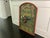 An arched wooden sign painted in olive green with a burgundy border, advertising "Lord Wembly-Thorn's School of Expert...