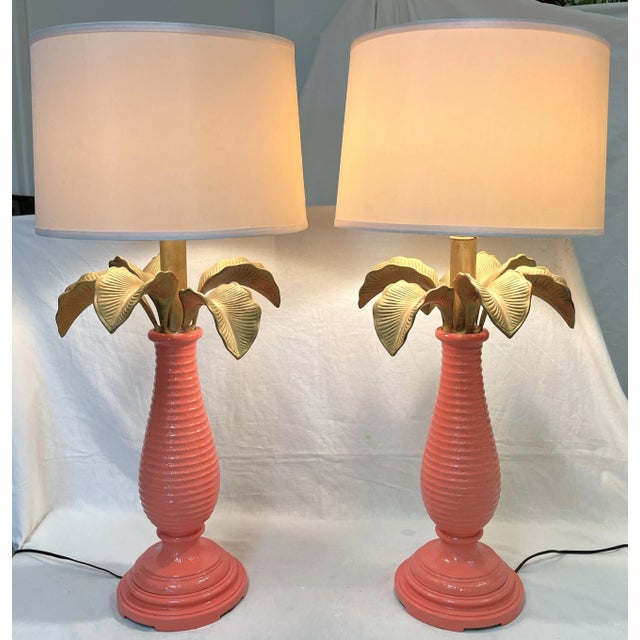 Trendsetting pair of Hollywood Regency style table lamps. They are made of metal with a palm tree motif. Each has grand...