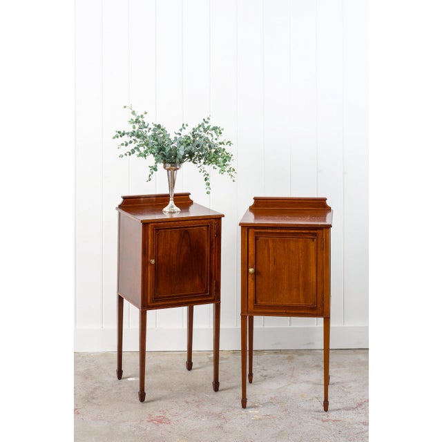Each mahogany bedside cupboard features a single-paneled door with a petite brass knob and backsplashes that add a small...