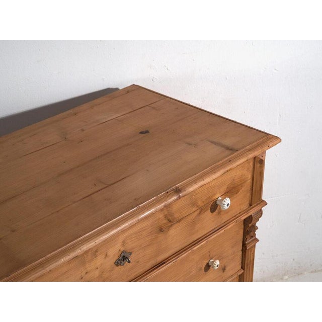This antique chest of drawers in solid pine is a European storage piece from the early 20th century, originally designed...