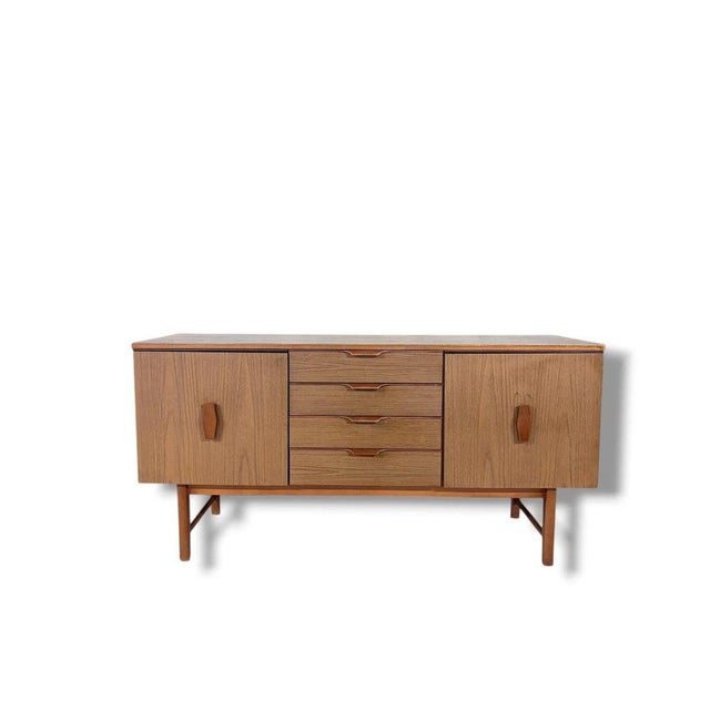 This vintage teak sideboard from the 1970s is a perfect blend of style and function, designed to enhance your living space...