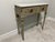 Elegant vintage Louis XVI-style console table featuring an antiqued gray-beige painted wood finish with gilt accents and...