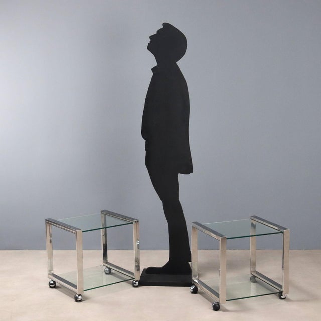 Pair of trolleys that can also be used as bedside tables with an aluminum frame, glass top, and wheels. This piece is...