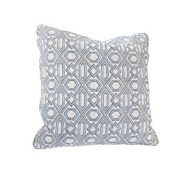 The pillows are a geometric pattern with a soft, neutral palette — primarily light gray/blue and white tones. The design...