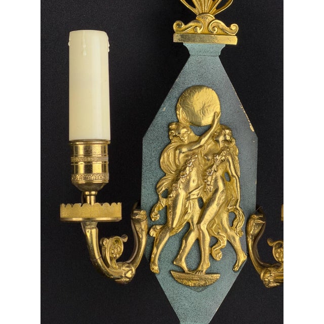 Elegant early 20th-century French neoclassical wall sconce crafted in gilt bronze and featuring a detailed central relief...