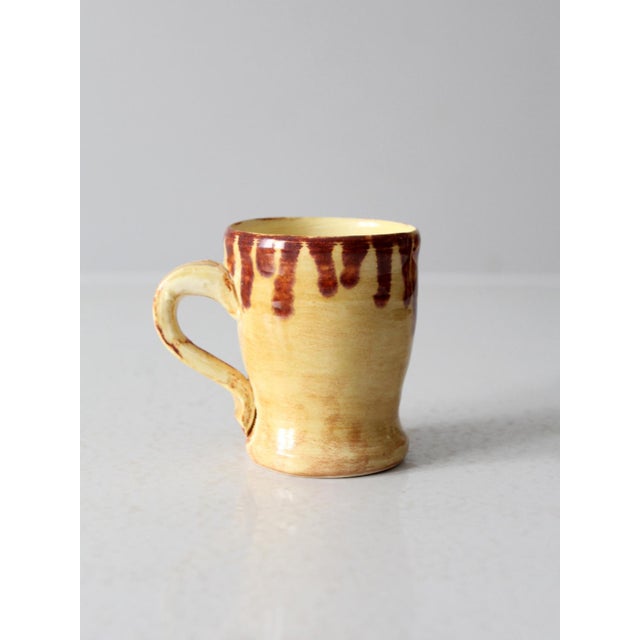This vintage handmade studio pottery mug is finished in a warm golden glaze with expressive brown drips along the rim,...