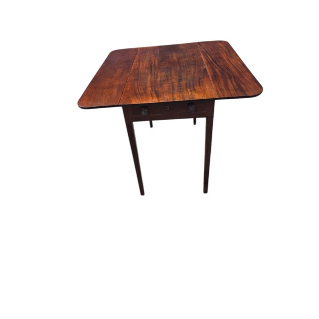 This late 18th century English walnut Sheraton drop leaf table is a fully assembled antique piece with an antique brass...