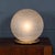 An elegant spherical frosted glass table lamp, crafted in Italy circa 1980. The globe features soft white striations that...
