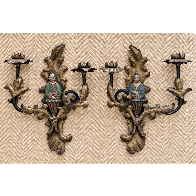 Pair of vintage Chinoiserie-style gilt metal candle wall sconces with colorful figural centers, sculptural foliage, and...